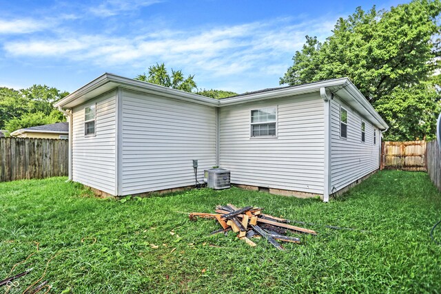 rear view of house featuring a lawn and central AC unit