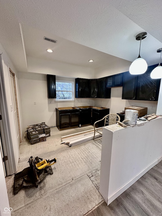 kitchen featuring decorative light fixtures, kitchen peninsula, a textured ceiling, and light hardwood / wood-style flooring