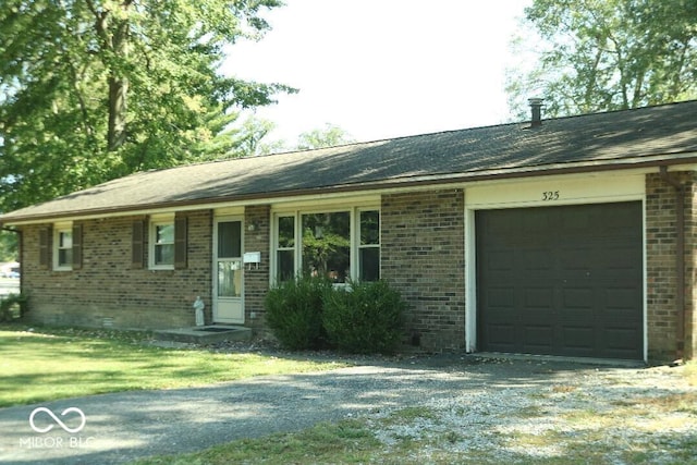 single story home with driveway, brick siding, and an attached garage