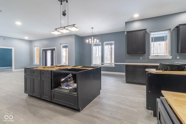 kitchen featuring light hardwood / wood-style flooring, a notable chandelier, pendant lighting, and a kitchen island