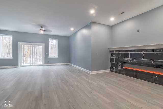 unfurnished living room featuring ceiling fan, a fireplace, and light hardwood / wood-style floors