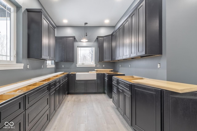 kitchen with hanging light fixtures, sink, and light hardwood / wood-style floors