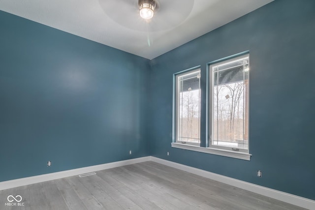 spare room featuring ceiling fan, a healthy amount of sunlight, and light hardwood / wood-style floors