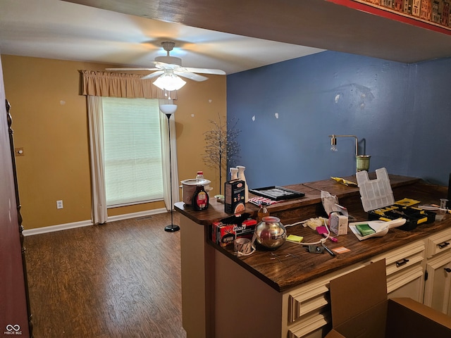 unfurnished office with ceiling fan and dark wood-type flooring