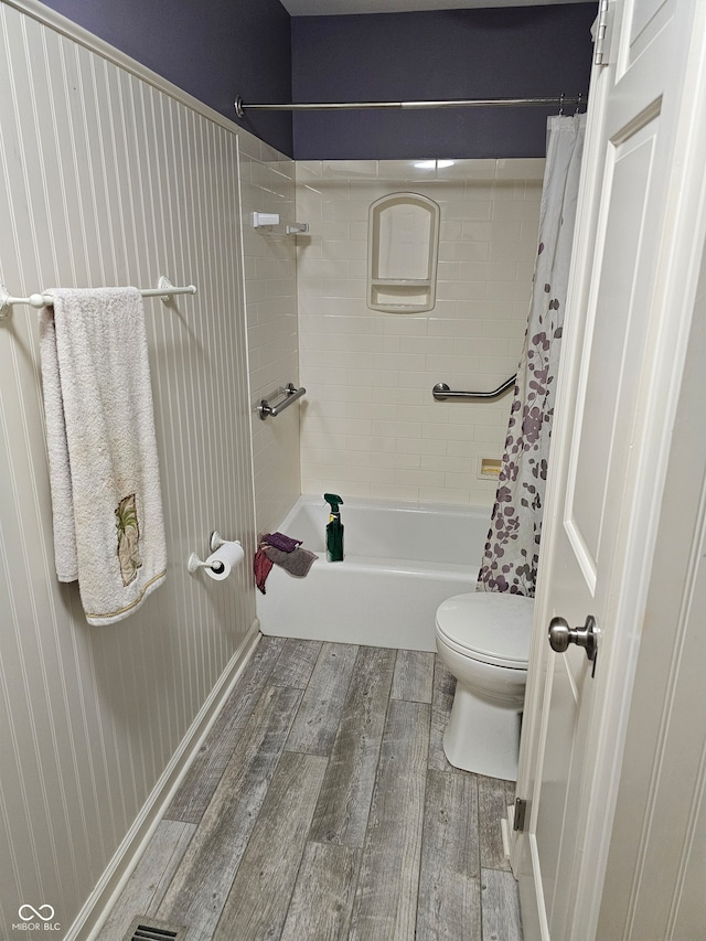 bathroom featuring toilet, shower / bathtub combination with curtain, and hardwood / wood-style floors