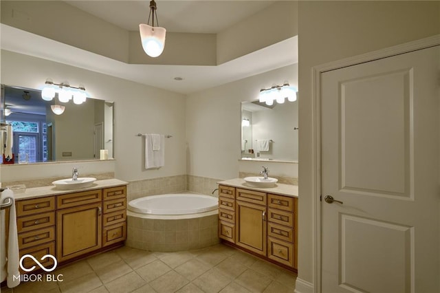 bathroom with tile patterned flooring, vanity, and tiled bath