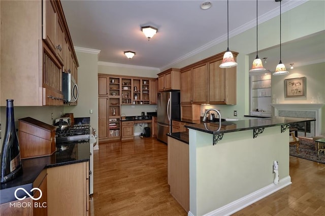 kitchen featuring appliances with stainless steel finishes, a kitchen bar, decorative light fixtures, kitchen peninsula, and light wood-type flooring