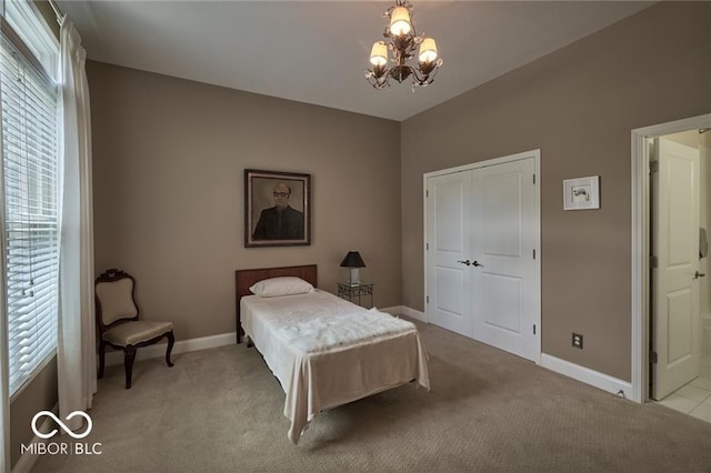 carpeted bedroom with connected bathroom, a chandelier, and a closet