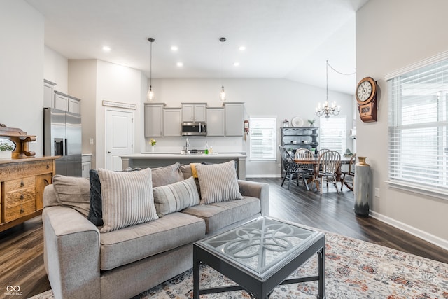 living room featuring dark wood-type flooring, lofted ceiling, and a chandelier