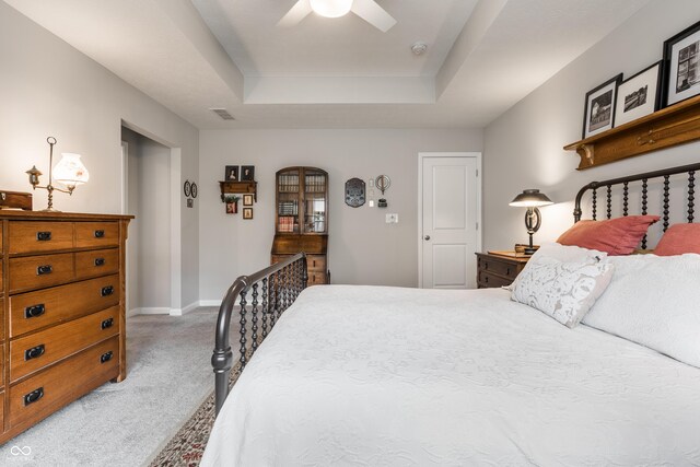 carpeted bedroom featuring ceiling fan and a tray ceiling