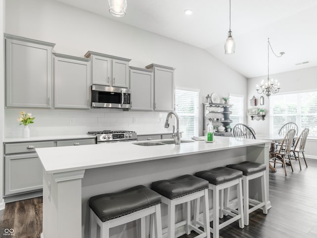 kitchen featuring lofted ceiling, hanging light fixtures, stainless steel appliances, and a kitchen bar