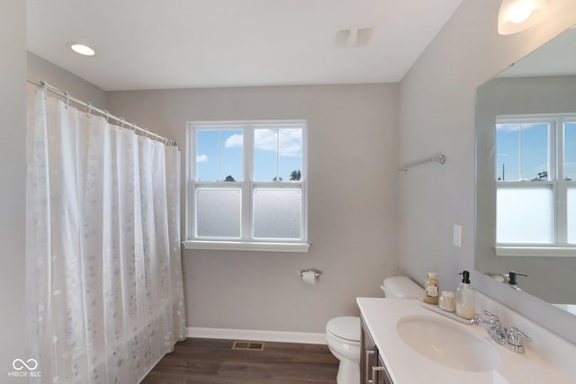 bathroom featuring toilet, vanity, wood-type flooring, and plenty of natural light