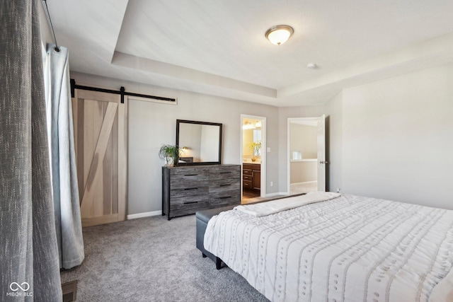 bedroom with ensuite bath, a barn door, light carpet, and a raised ceiling