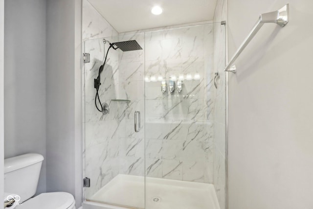 bathroom featuring a shower with shower door and toilet