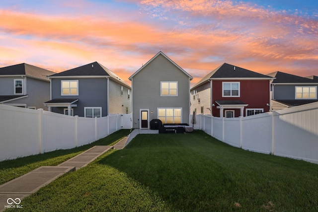 back house at dusk featuring a lawn