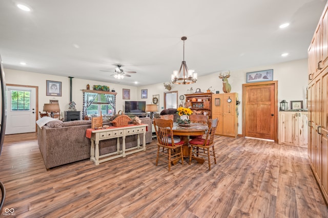 dining area with ceiling fan with notable chandelier and wood-type flooring