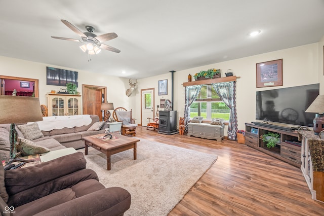 living room with ceiling fan, hardwood / wood-style floors, and a wood stove