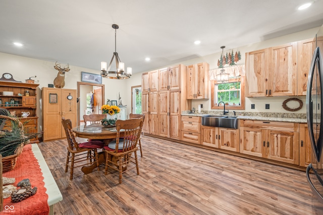 dining room with sink, wood-type flooring, and a notable chandelier