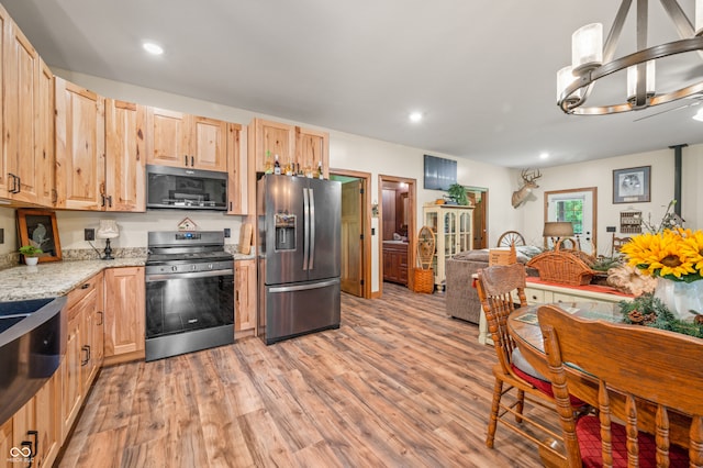 kitchen with light stone countertops, light brown cabinets, appliances with stainless steel finishes, and light wood-type flooring