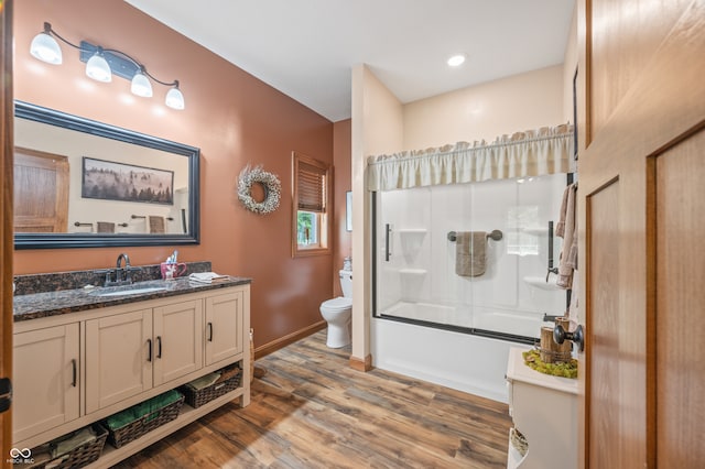 full bathroom with hardwood / wood-style flooring, shower / bath combination with glass door, toilet, and vanity