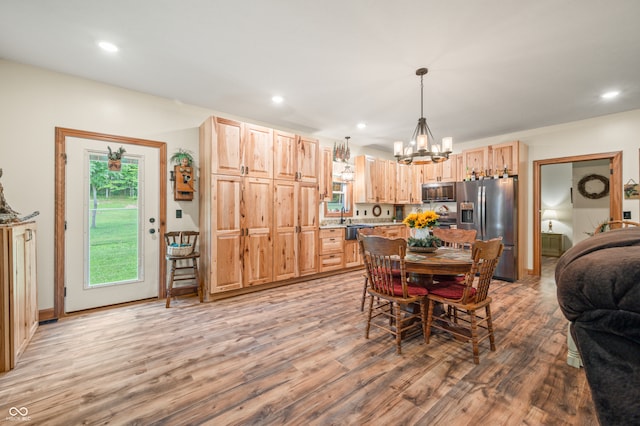 dining room with an inviting chandelier, sink, and light hardwood / wood-style flooring