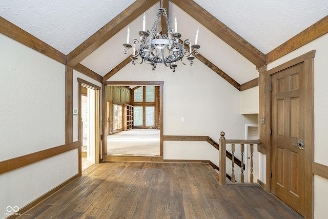 interior space featuring dark wood-style floors, a textured ceiling, baseboards, and vaulted ceiling with beams