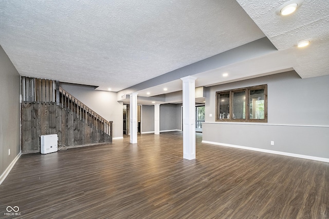 below grade area with stairs, a textured ceiling, wood finished floors, and baseboards