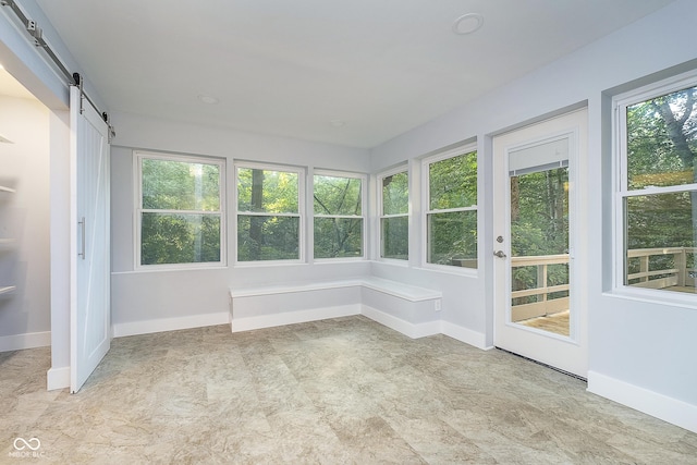 unfurnished sunroom featuring a barn door