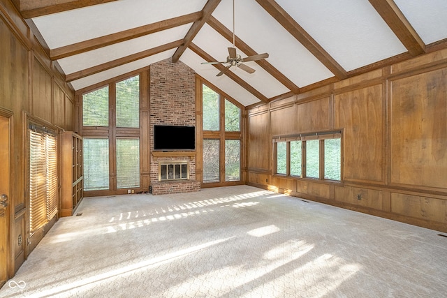 unfurnished living room featuring a brick fireplace, light carpet, wooden walls, high vaulted ceiling, and beamed ceiling