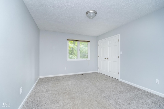 carpeted empty room with visible vents, baseboards, and a textured ceiling