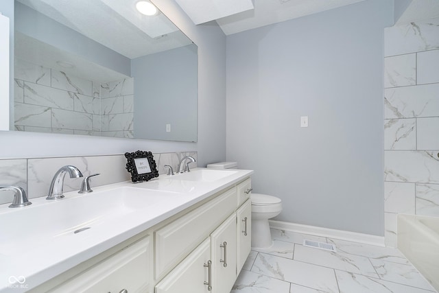 full bath with marble finish floor, visible vents, toilet, a sink, and baseboards