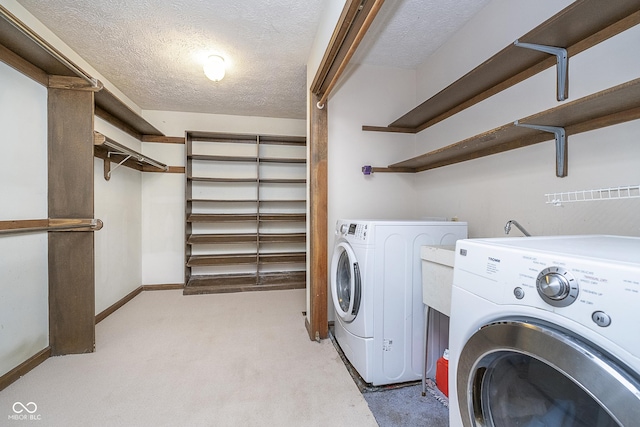 washroom with washing machine and clothes dryer, light carpet, a textured ceiling, laundry area, and baseboards