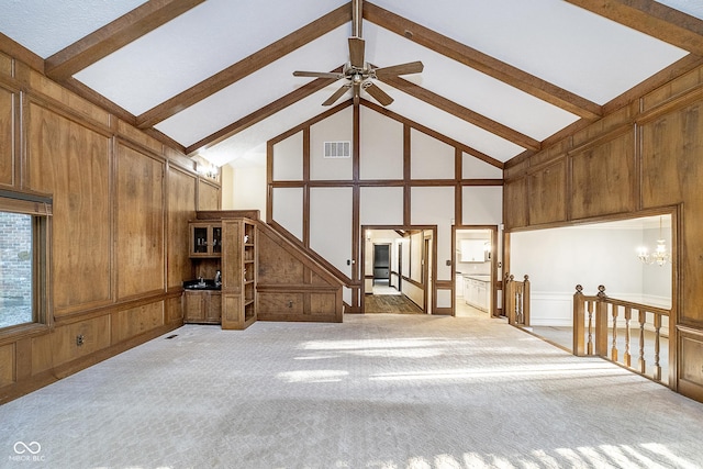 unfurnished living room with visible vents, light colored carpet, high vaulted ceiling, a decorative wall, and beam ceiling