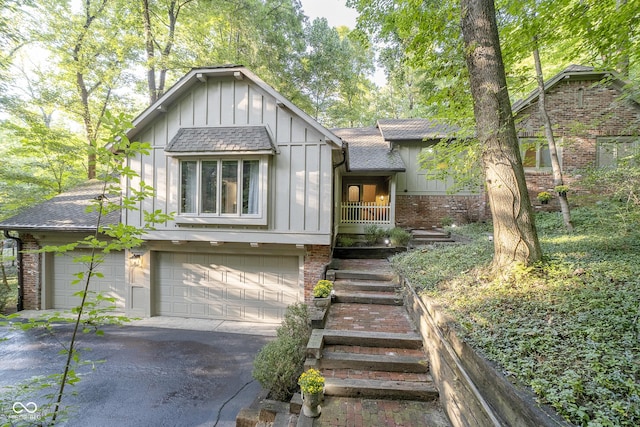 english style home featuring board and batten siding, brick siding, a shingled roof, and a garage