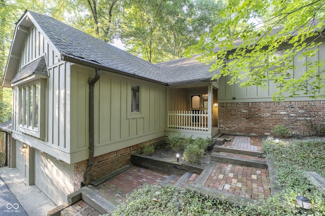 view of side of home with an attached garage, a shingled roof, and board and batten siding