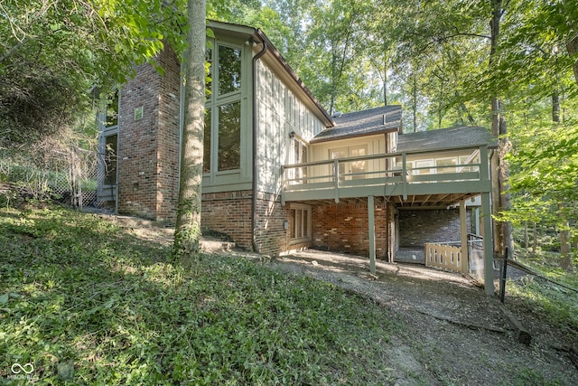 back of property with a carport, brick siding, and a wooden deck