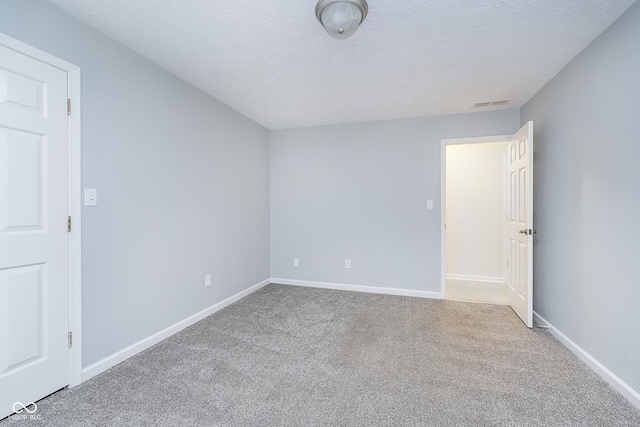 empty room featuring a textured ceiling, carpet floors, visible vents, and baseboards