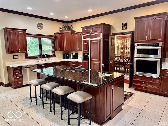 kitchen featuring stainless steel appliances, a breakfast bar area, a kitchen island, and dark stone countertops