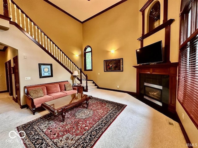 carpeted living room with crown molding, a tile fireplace, and a high ceiling