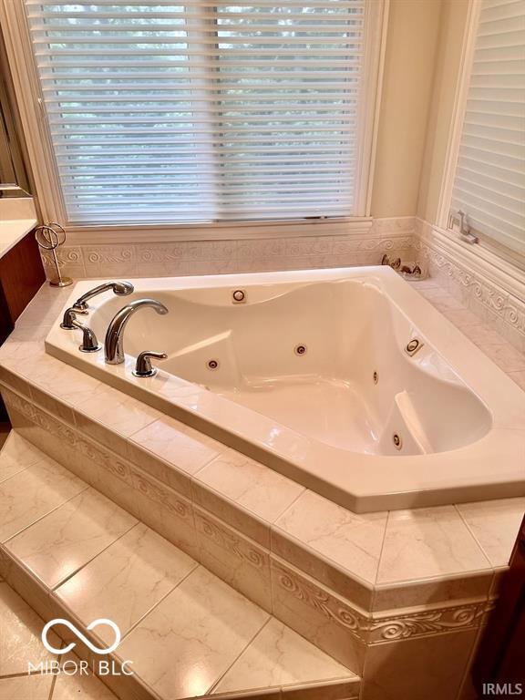 bathroom featuring vanity and a relaxing tiled tub