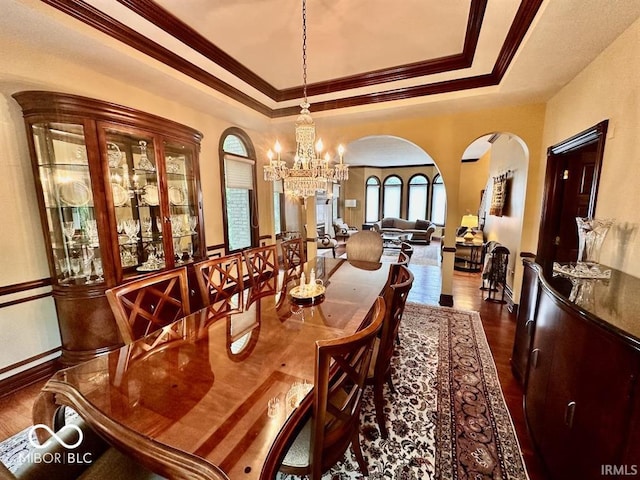 dining area featuring a raised ceiling, ornamental molding, dark hardwood / wood-style floors, and a chandelier