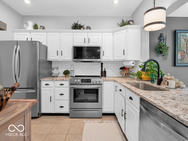 kitchen with light tile patterned floors, stainless steel appliances, light stone countertops, decorative backsplash, and sink