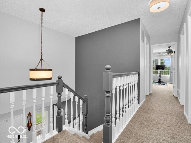 corridor with light colored carpet and a textured ceiling