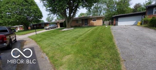 ranch-style house with a garage and a front lawn