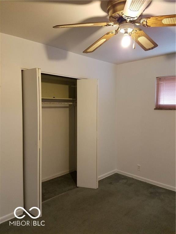 unfurnished bedroom with ceiling fan, dark carpet, and a closet