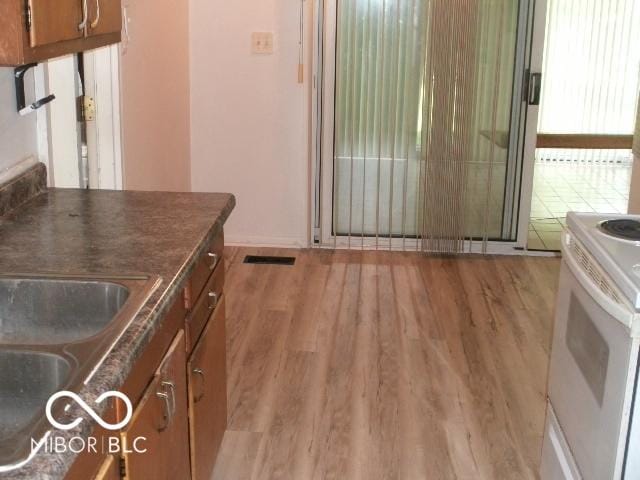 kitchen featuring sink, light hardwood / wood-style flooring, and electric range