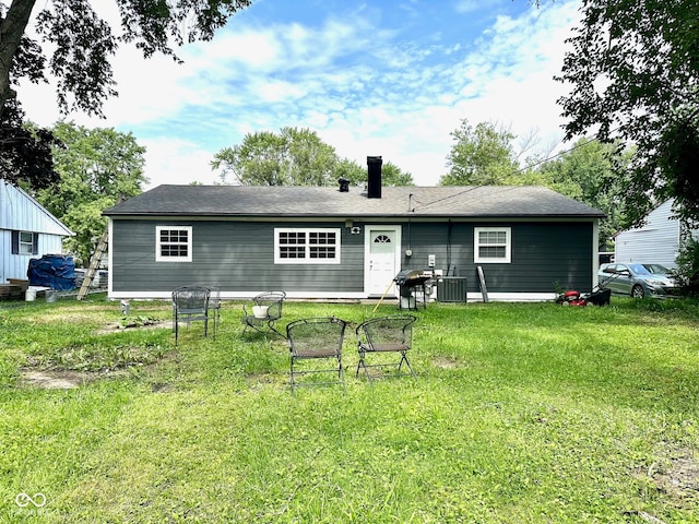 rear view of property with central AC unit and a lawn