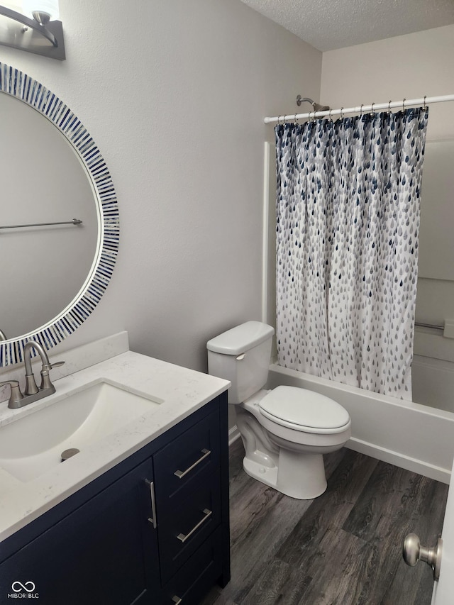 full bathroom with hardwood / wood-style flooring, shower / tub combo, vanity, a textured ceiling, and toilet