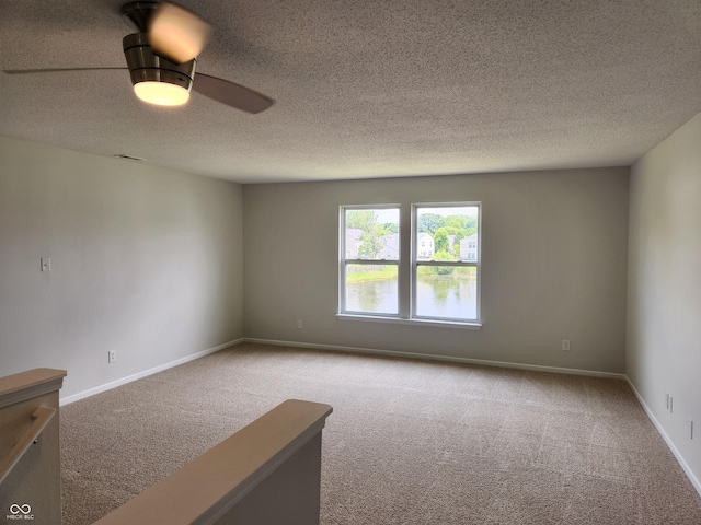 carpeted spare room with a textured ceiling and ceiling fan