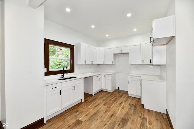 kitchen featuring backsplash, light hardwood / wood-style floors, sink, and white cabinets